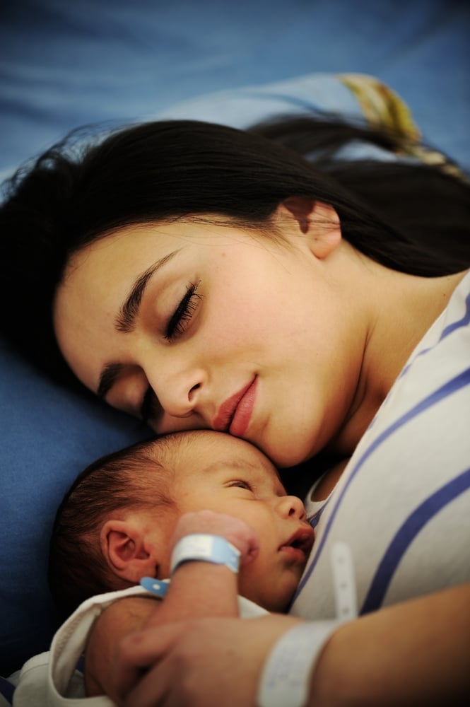 Alt-Text: Mutter hält ihr schlafendes Neugeborenes im Arm – Soforthilfe durch den kostenlosen Schlafguide für Babys von Schlummerwolke.